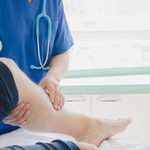 Doctor examining a patient’s lower leg in a clinical setting
