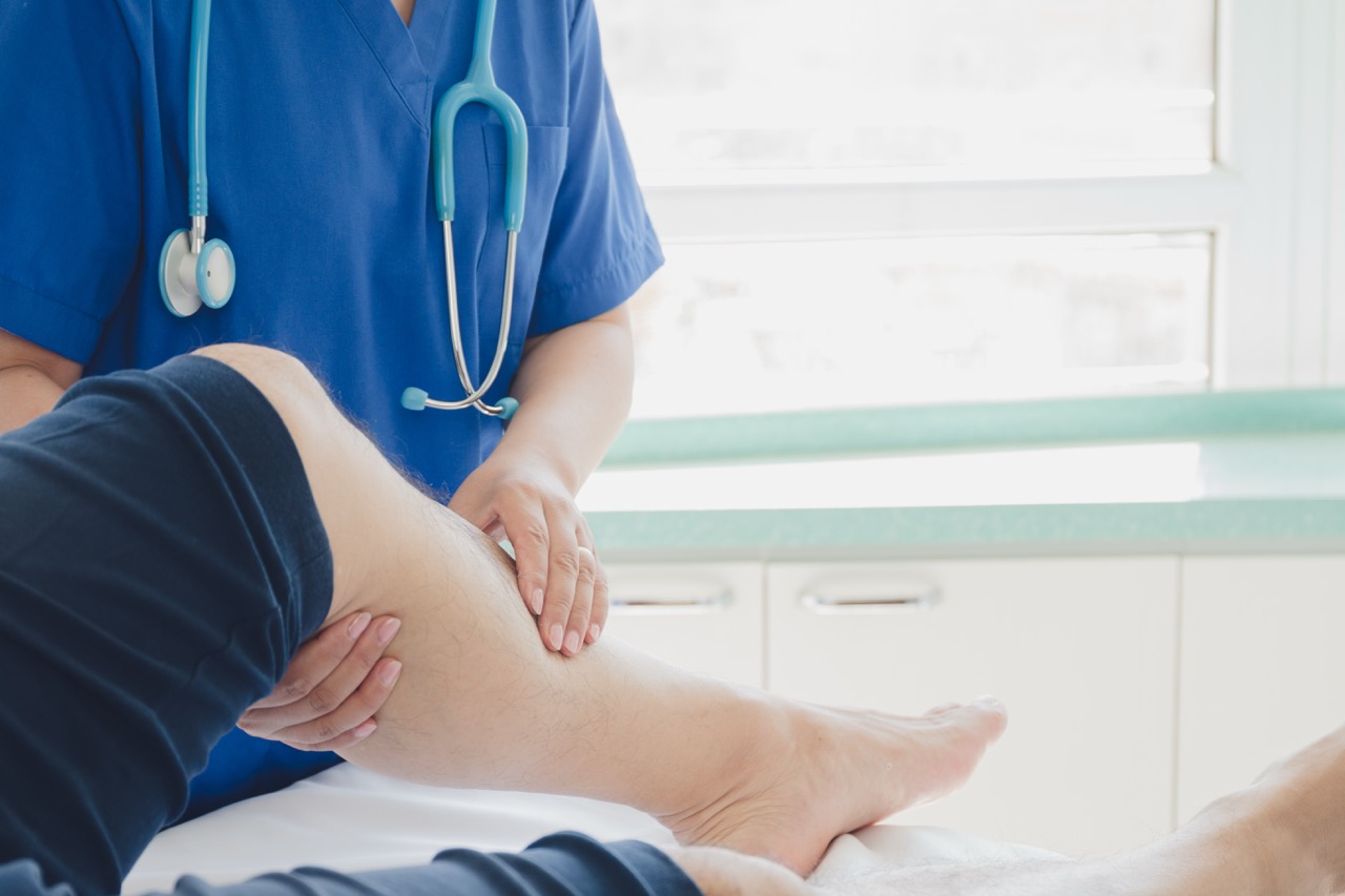 Doctor examining a patient’s lower leg in a clinical setting