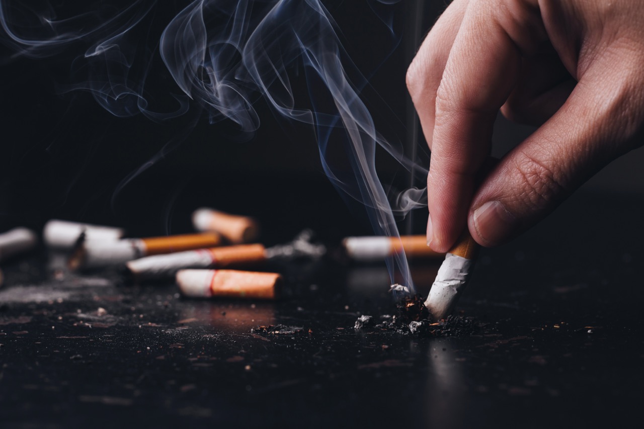 Close-up of a person holding a lit cigarette, illustrating the connection between tobacco use and vascular health risks.
