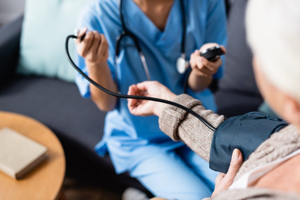 Nurse measuring the blood pressure of an elderly patient using a tonometer cuff on her arm.