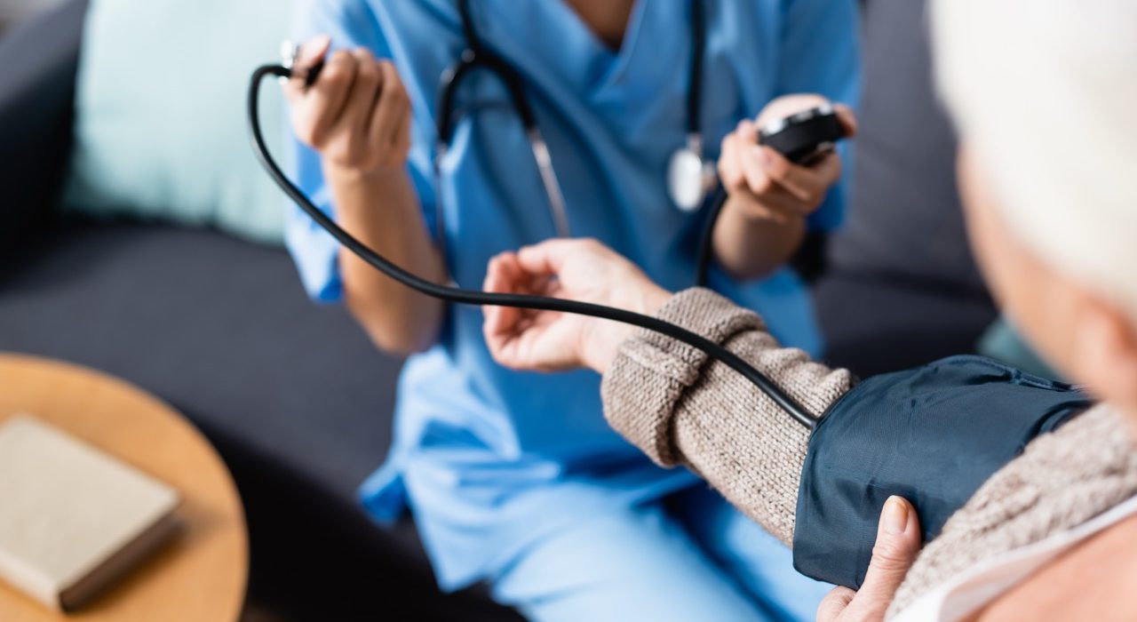 Nurse measuring the blood pressure of an elderly patient using a tonometer cuff on her arm.